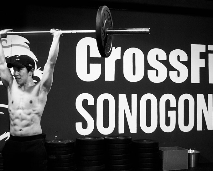 Male athlete lifting a barbell overhead in a CrossFit gym